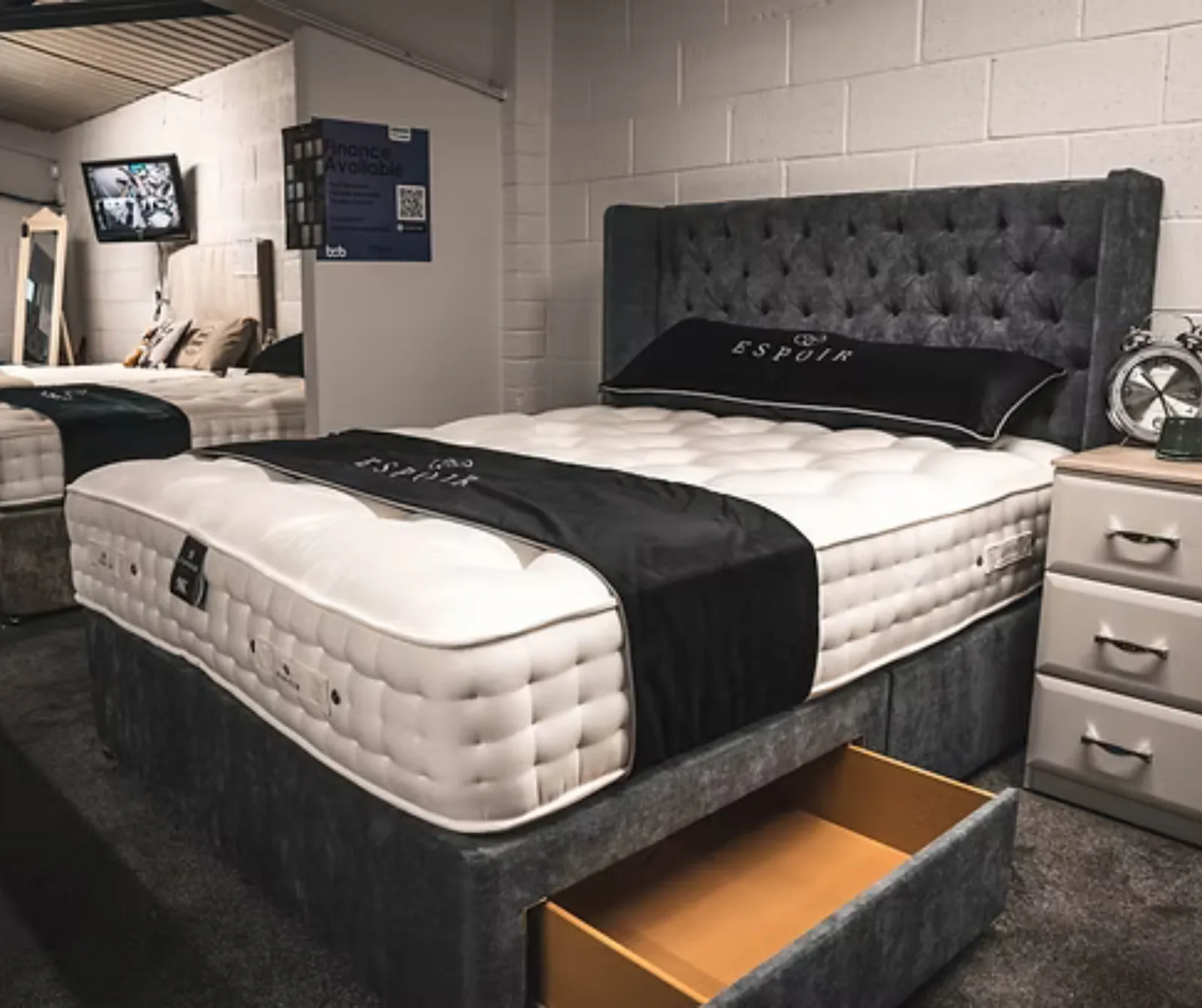 A divan bed with a tall buttoned headboard on display in the Boundary Carpets and Beds showroom in Colne