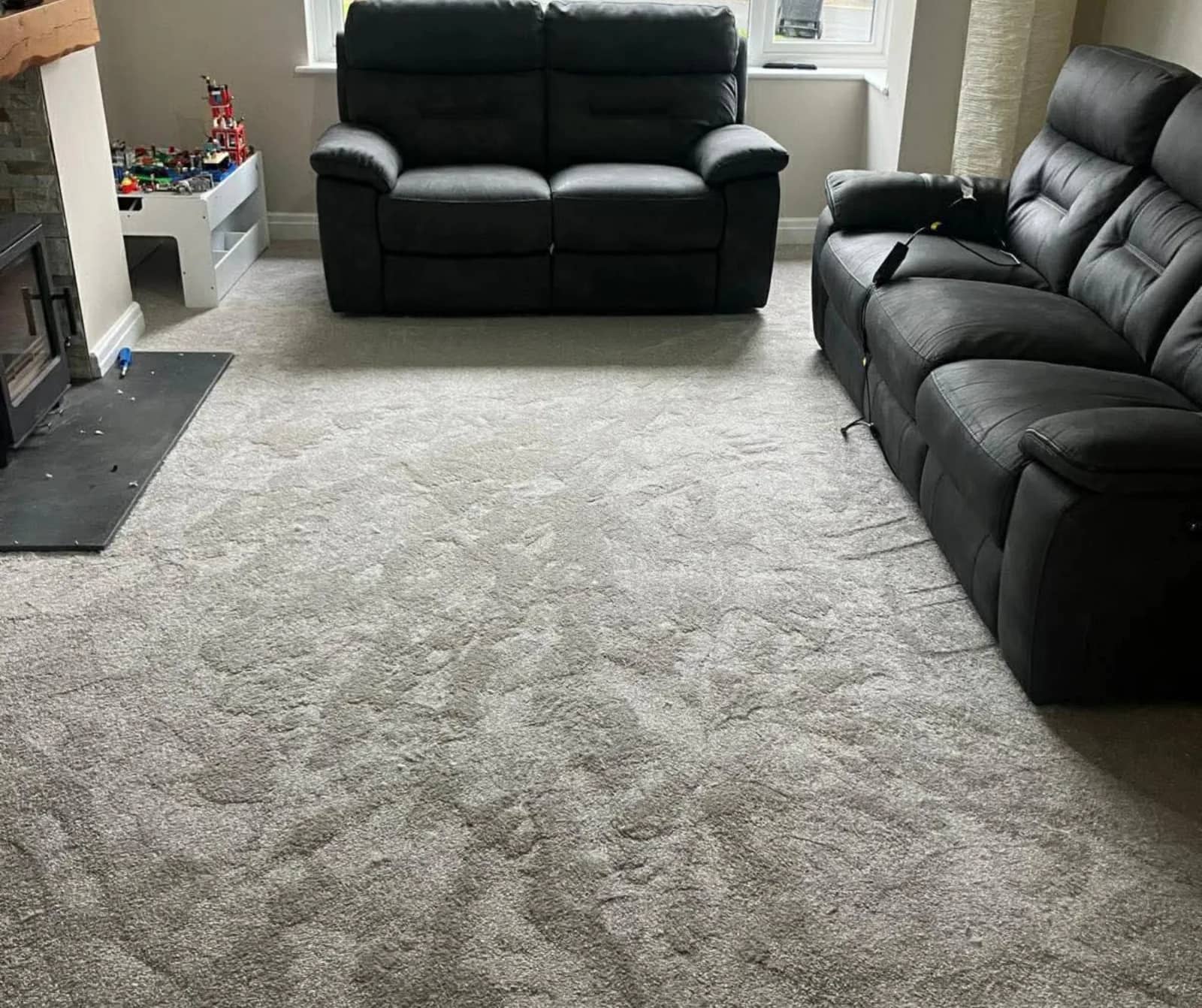 A deep pile grey carpet fitted wall to wall in a living room with leather sofas
